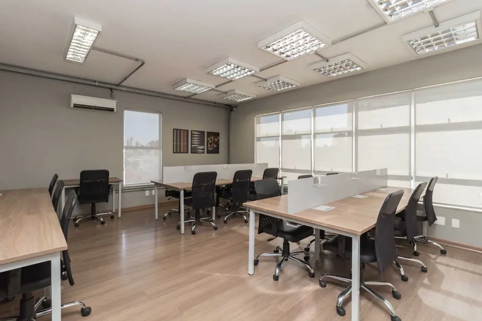 Área de estações de trabalho do Desk Coworking em Belo Horizonte, com mesas compartilhadas e área de convivência.